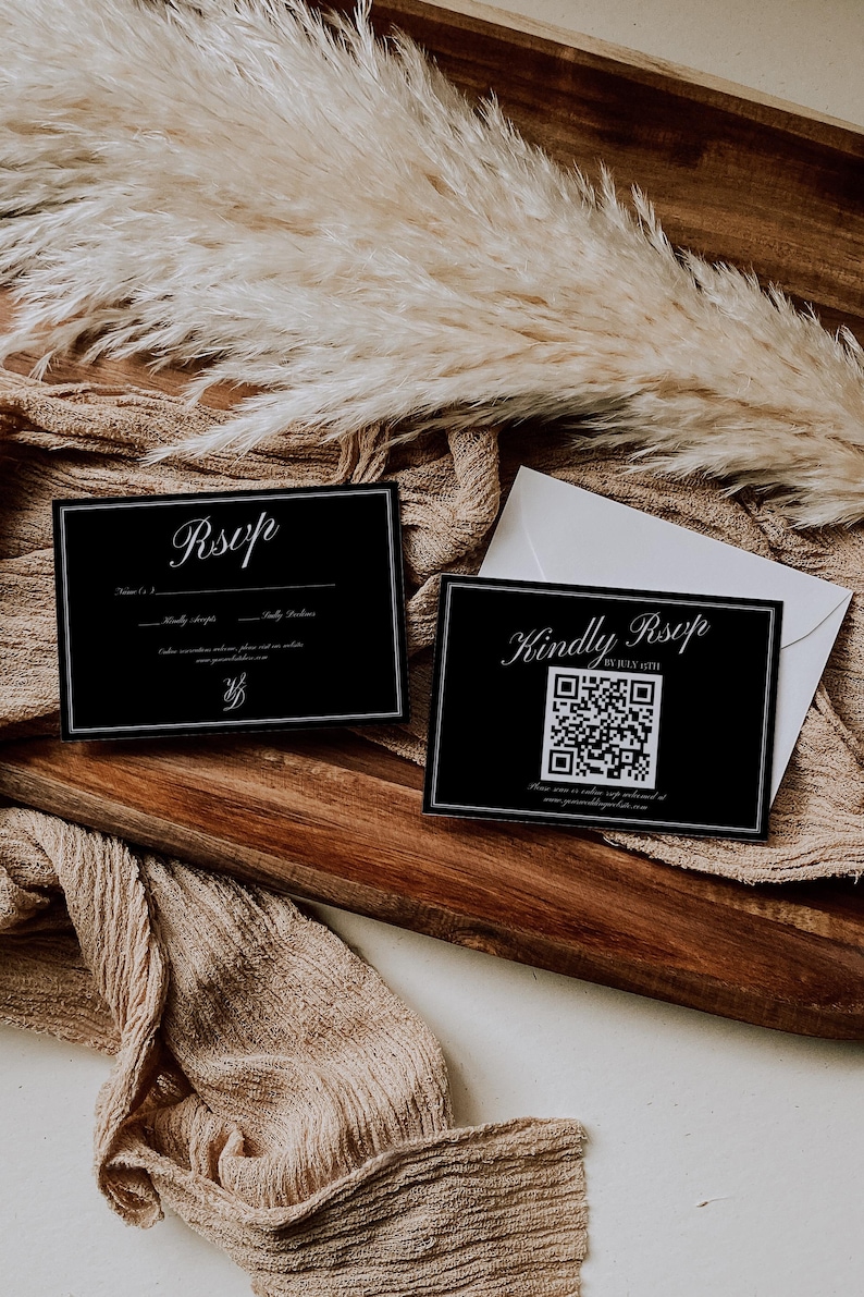 May include: Two black RSVP cards with white text and a QR code, resting on a wooden tray with a beige cloth and dried plants. One card says "Kindly RSVP" and the other says "RSVP".