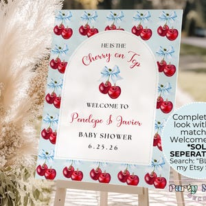 May include: A blue and white baby shower sign with a cherry theme. The sign says "He is the Cherry on Top" and "Welcome to Penelope & Javier Baby Shower 6.25.26".