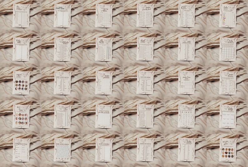 May include: A collection of beige baby shower game cards with various designs and text. The cards are arranged on a textured, neutral-toned surface, with dried plants. The cards feature different games and activities.