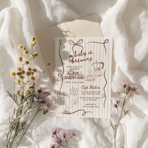 May include: A baby shower invitation with the text "a baby is brewing" and illustrations of a coffee pot, baby bottle, and coffee cup. The invitation is on a striped background with floral accents.