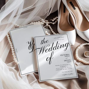 May include: Elegant wedding invitation with the words "the Wedding of" in elegant script. The invitation is white with a black border, and the text includes the names Victoria Robinson and Devyn Nguyen. White high heels and a pearl necklace are also in the image.