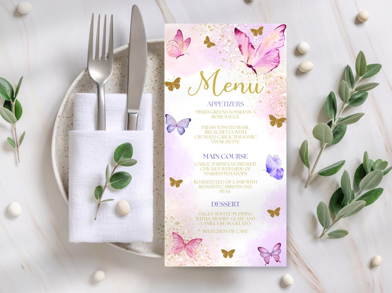 May include: A menu card with a butterfly theme. The menu features a pink and gold color scheme with butterfly illustrations. The menu includes appetizers, main course, and dessert options. A fork, knife, and napkin are on a plate to the left.