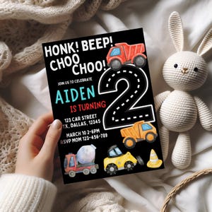 K&ouml;nnte beinhalten: Eine schwarz-wei&szlig;e Geburtstagseinladung mit einer gro&szlig;en Zahl 2 auf einer Stra&szlig;e. Die Einladung lautet "Honk! Beep! Choo Choo!" und "Aiden wird 2 Jahre alt". Auf der Stra&szlig;e sind Baufahrzeuge zu sehen und oben steht der Text "Feiern Sie mit uns".