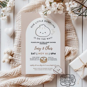 May include: A baby shower invitation with a light brown background featuring a cartoon dumpling with a smiling face. The text reads "Our Little Dumpling is on the way!" and includes details about the event, such as the date, time, and location.