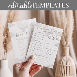 May include: Two baby shower game cards with watercolor cloud designs. One card is titled "Baby Trivia" and the other is "Predictions & Advice" with fill-in-the-blank sections for baby's details. The cards are held by a person.