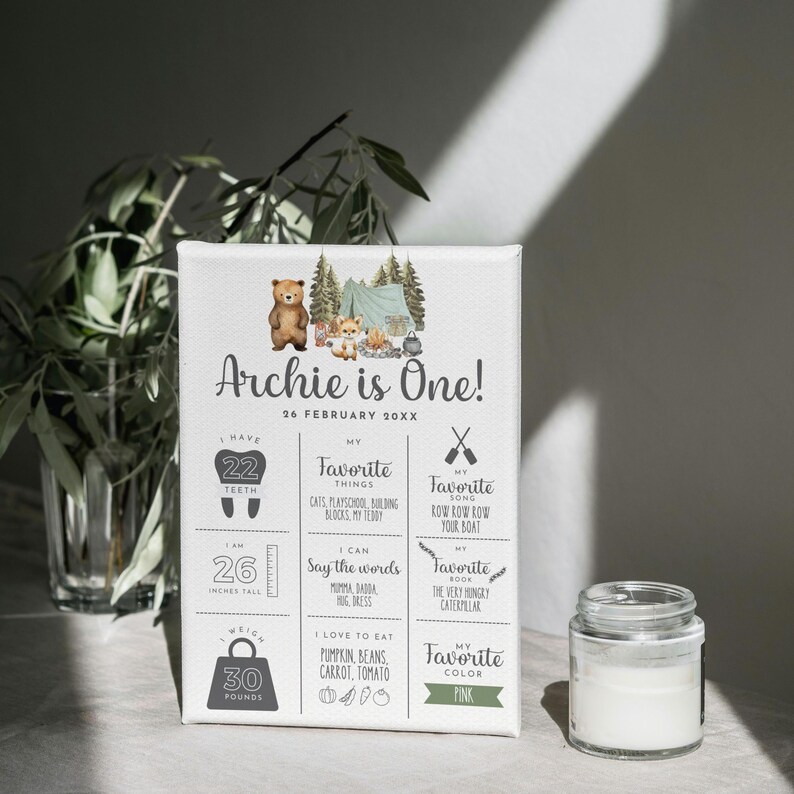 May include: A personalized first birthday chart for a boy named Archie. The chart features a woodland theme with a bear, a tent, and trees. It includes details about Archie's age, height, weight, favorite things, and favorite color. The text on the chart reads "Archie is One! 26 February 20XX".