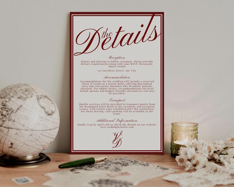 May include: A wedding details card with a burgundy border and text. The card includes information about the reception, accommodation, and transport. A globe, pen, and candle are in the background.