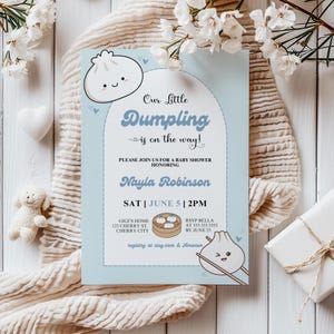 May include: A blue and white baby shower invitation with a cartoon dumpling illustration. The invitation reads "Our Little Dumpling is on the way!" and includes the date, time, and location of the shower.