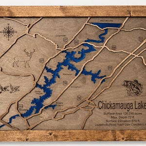 May include: A framed wooden topographic map of Chickamauga Lake featuring a blue resin water inlay, engraved road markers, a compass rose, and illustrations of a deer, ducks, and a fish. Text includes lake statistics and dam completion date.