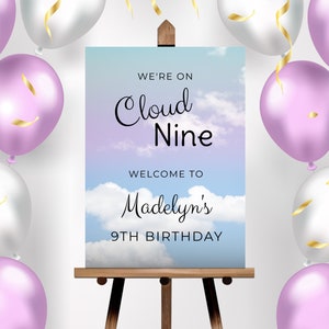 May include: A birthday party sign with a blue and purple sky background and white clouds. The sign says "We're on Cloud Nine" and "Welcome to Madelyn's 9th Birthday".