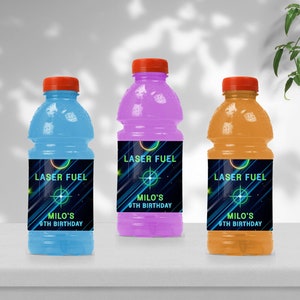 Op de afbeelding: Drie plastic waterflessen met etiketten waarop "Laser Fuel" en "Milo's 9th Birthday" staat. De flessen zijn blauw, paars en oranje.