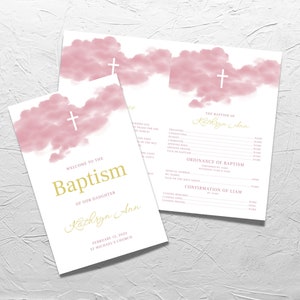 May include: A pink and white baptism program with a watercolor cloud design and a gold cross. The program includes the text "Welcome to the Baptism of our daughter Kathryn Ann" and the date "February 12, 2023".