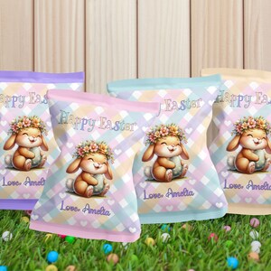 May include: Four colorful Easter-themed chip bags. Each bag features a cartoon bunny wearing a flower crown and holding an egg. The bags have a pastel plaid pattern and the text "Happy Easter" and "Love, Amelia".