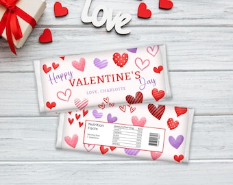 May include: A white chocolate bar wrapper with a pink, red, and purple heart pattern. The wrapper says "Happy Valentine's Day" and "Love, Charlotte". The back of the wrapper has a nutrition facts label with a list of "Amount/Serving" including "Family", "Friends", "Hugs", "Kisses", "Love", "Wishes", and "Zovs".