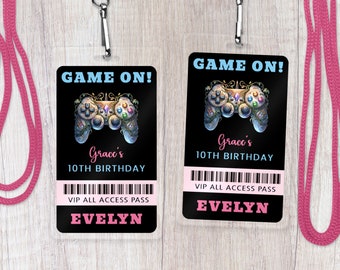 May include: Two black and white plastic game controller birthday party favour badges with a pink lanyard. The badges have a colourful game controller graphic and the text "GAME ON!" in blue. The text "Grace's 10th Birthday" and "VIP All Access Pass" is in pink. The name "Evelyn" is printed in pink on each badge.