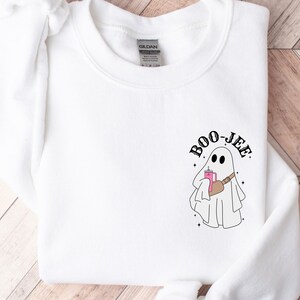 May include: White sweatshirt with a ghost graphic and the text 'BOO-JEE'.