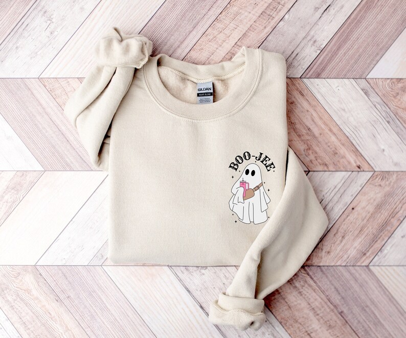 May include: A beige sweatshirt with a ghost graphic and the text 'BOO-JEE'.
