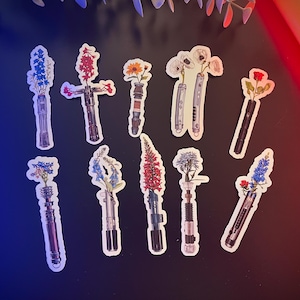 May include: Ten colourful floral lightsaber stickers with different flower arrangements. The stickers are on a blue and red background.