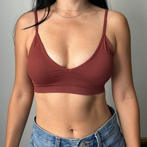 May include: A rust-colored ribbed bralette with a V-neckline. The bralette is made of a soft, stretchy fabric and has adjustable straps.