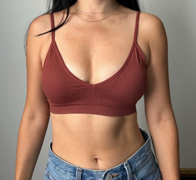 May include: A rust-colored ribbed bralette with a V-neckline. The bralette is made of a soft, stretchy fabric and has adjustable straps.