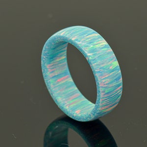 May include: A turquoise blue ring with a swirling pattern of white and pink opal.