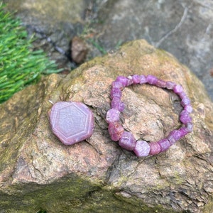 Peut inclure: Un ensemble de bracelet et pendentif en pierres précieuses violettes. Le bracelet est composé de pierres précieuses violettes facettées et le pendentif est une pierre précieuse de forme hexagonale.