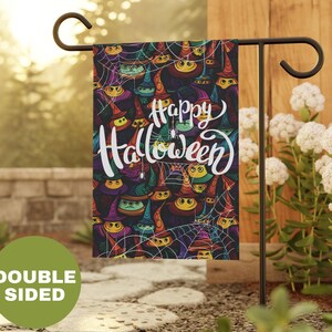 May include: A colorful garden flag with a black background and a pattern of witches' hats and spiderwebs. The text "Happy Halloween" is written in white cursive letters.