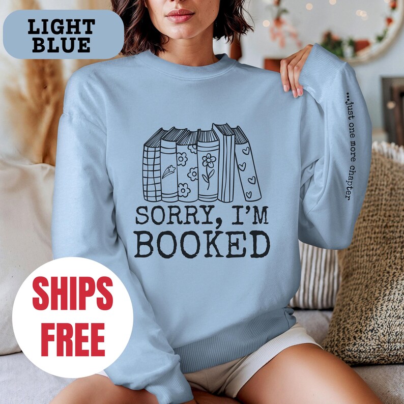 May include: Light blue sweatshirt with a stack of books and the text "Sorry, I'm Booked" and "...just one more chapter".