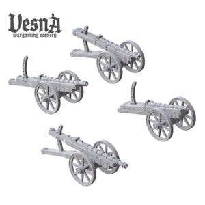 May include: Four gray miniature cannons with spoked wheels, designed for wargaming scenery. The cannons are arranged on a white background. The text "Vesna wargaming scenery" is in the upper left corner.