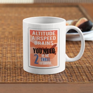 May include: White ceramic mug with a graphic of a plane in the clouds. The text reads "Altitude Airspeed Brains You Need 2 of the Three to Survive".