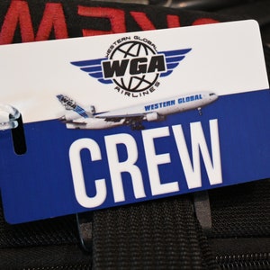 May include: A white and blue crew tag with the Western Global Airlines logo and the word "CREW" in large white letters.