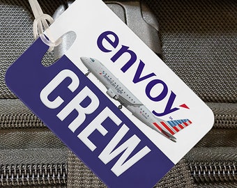 May include: White luggage tag with blue and white text that reads "envoy" and "CREW". A small airplane with the text "American Eagle" is printed on the tag.