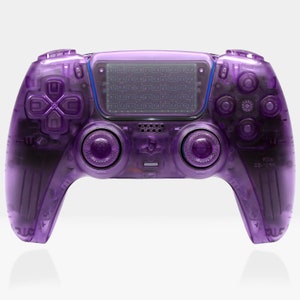 Puede incluir: Un mando inalámbrico PlayStation 5 DualSense translúcido morado con agarre texturizado. El mando tiene un panel táctil y botones morados.