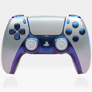 Puede incluir: Un mando de PlayStation 5 blanco y azul con un acabado iridiscente. El mando tiene un logotipo de PlayStation azul y botones azules.