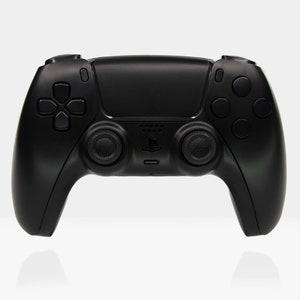 May include: A black wireless game controller with a PlayStation logo. The controller has two analogue sticks, a D-pad, and several buttons.