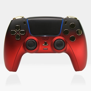 Könnte beinhalten: Ein roter und schwarzer PlayStation 5 DualSense Wireless-Controller mit goldenen Akzenten. Der Controller hat ein schwarzes Touchpad und zwei schwarze Tasten.