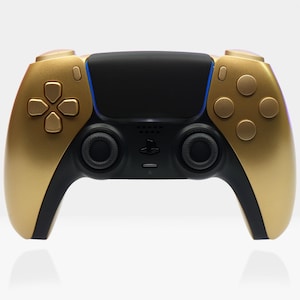 Op de afbeelding: Een gouden en zwarte draadloze gamecontroller. De controller heeft een gouden frontplaat met een zwart middengedeelte. De knoppen en het D-pad zijn goudkleurig. De controller heeft een blauwe accentkleur.