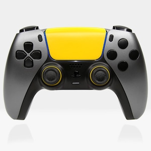 May include: A grey and black video game controller with yellow faceplates. The controller has two analogue sticks, a D-pad, and several buttons.