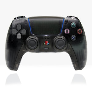 Könnte beinhalten: Ein schwarzer PlayStation 5 DualSense Wireless-Controller mit transparentem Design. Der Controller verfügt über ein PlayStation-Logo, ein Touchpad und Tasten für Navigation und Gameplay.