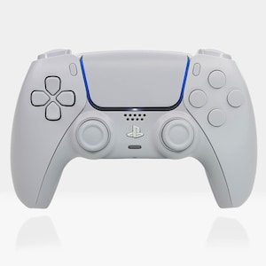 Może przedstawiać: Biały bezprzewodowy kontroler DualSense do PlayStation 5 z niebieskim akcentem na touchpadzie. Kontroler ma standardowy układ z dwoma analogowymi gałkami, krzyżakiem, przyciskami funkcyjnymi i przyciskami na ramionach.