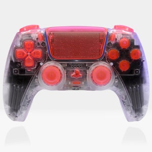 以下が含まれることがあります： 赤いボタンと赤いアナログスティックが付いた、透明な黒と赤のPlayStation 5 DualSenseコントローラーです。