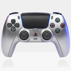 May include: A silver PlayStation 5 DualSense wireless controller with black buttons and a blue light bar. The controller has a PlayStation logo on the front.