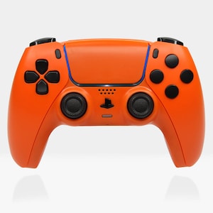 May include: An orange PlayStation 5 DualSense wireless controller with black buttons and a black PlayStation logo. The controller has a textured grip and a smooth, glossy finish.