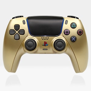 May include: A gold-colored PlayStation 5 DualSense wireless controller. The controller has a black touchpad and black buttons with blue and red accents.