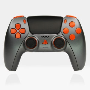 Könnte beinhalten: Ein schwarzer PlayStation 5-Controller mit orangenen Knöpfen. Der Controller hat eine strukturierte Oberfläche und ein PlayStation-Logo auf der Vorderseite.