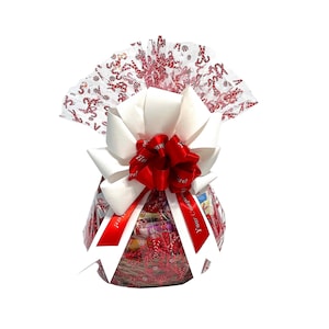 May include: A white gift basket filled with various treats and wrapped in red and white candy cane patterned cellophane. A large white bow with a red ribbon is tied on top. The cellophane has the text "Your Christmas Gift!" printed on it.