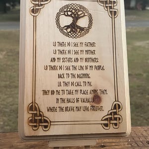 May include: A wooden plaque with a Celtic knot design and a tree of life image. The plaque features a poem about Valhalla, the Norse afterlife, with the text: "LO THERE DO I SEE MY FATHER: LO THERE DO I SEE MY MOTHER AND MY SISTERS AND MY BROTHERS: LO THERE DO I SEE THE LINE OF MY PEOPLE. BACK TO THE BEGINNING. LO. THEY DO CALL TO ME. THEY BID ME TO TAKE MY PLACE AMONG THEM. IN THE HALLS OF VALHALLA WHERE THE BRAVE MAY LIVE FOREVER."