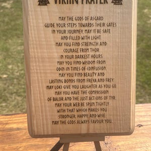 May include: A wooden plaque with a Viking prayer engraved on it. The prayer is a traditional Norse blessing for strength, courage, and wisdom. The plaque is mounted on a small easel.