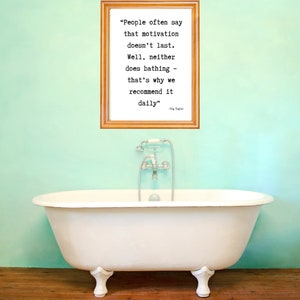 Puede incluir: Una bañera blanca con patas de león y un grifo plateado se encuentra frente a una pared de color verde azulado claro. Encima, una impresión enmarcada muestra la cita: "La gente suele decir que la motivación no dura..." El suelo es de madera.