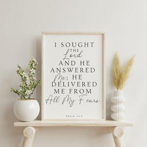 May include: A black and white printable wall art print with a religious quote from Psalm 34:4. The quote reads "I sought the Lord and he answered me; he delivered me from all my fears."